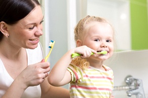 a mother teaching her baby to brush