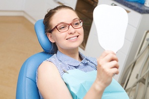 a woman admiring her smile at the dentist