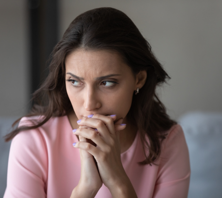 Woman with dark hair thinking, portraying how to get a refund from a dentist