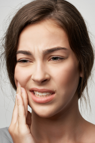 Woman frowning with her fingers on her cheek, portraying the need for toothache relief